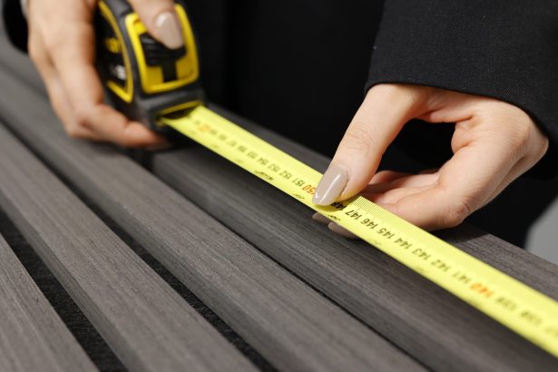 Hand Using Measuring Tape To Check Slat Wall Size For Installation